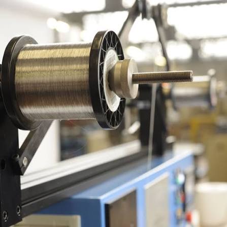 A precision coil winding machine with Kanthal A1 resistance wire feeding onto a mandrel
